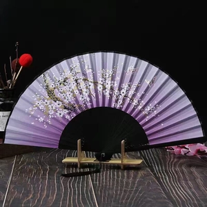 Macro detail of purple folding fan with cherry blossoms, butterflies and black silk tassel