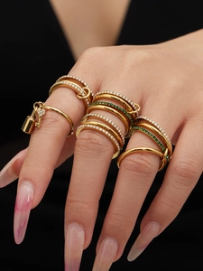 Detailed close-up of stacked gold rings with zircon stones and lock pendant on hand