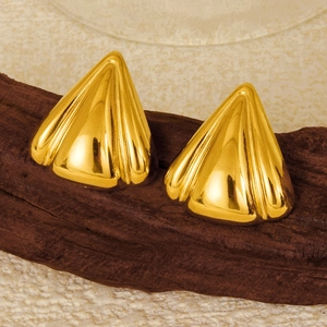Macro shot of gold geometric petal earrings with textured metal resting on dark wood