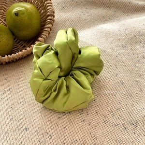 Détail d'un chouchou en satin de soie vert sur tricot beige avec décor de poire