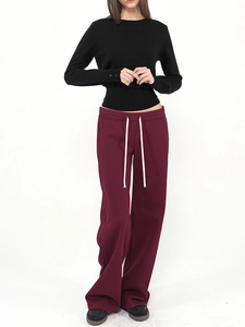 Slim fit black long sleeve sweater paired with dark red drawstring wide-leg pants