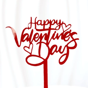 Macro shot of red acrylic Happy Valentine's Day cake topper with cursive heart design