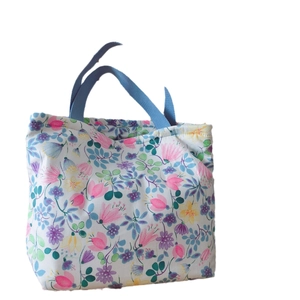 Stoffhandtasche mit Blumenmuster, blauen Henkeln und buntem Print auf weißem Grund