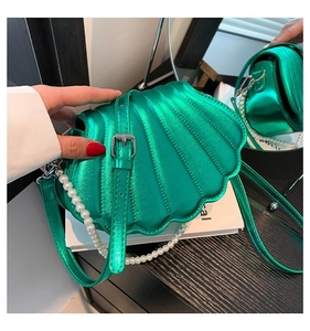 Detailansicht einer grünen muschelförmigen Umhängetasche mit Perlenkette und glänzendem PU