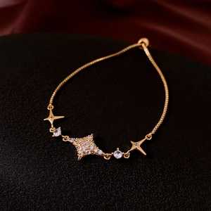Dettaglio di bracciale dorato con stella e zirconi con chiusura a cursore regolabile