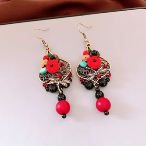 Vintage bohemian drop earrings with red resin roses and dragonfly charms on white background