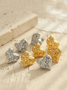 Detailaufnahme von Herzohrringen mit strukturierter Gold- und Silber Hammerschlag-Optik