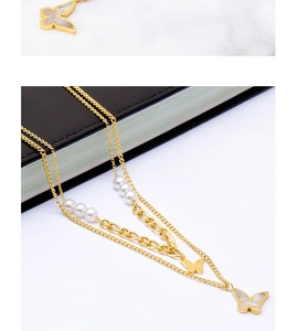Detail of layered gold butterfly necklace with elegant pearls and shell pendant detail
