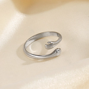 Minimalist silver hug ring with hands design on champagne silk background