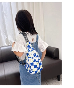 Detail view of a kids blue and white checkered chest bag with yellow bear and COOL print