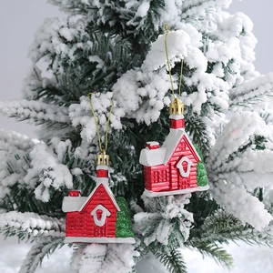 Adornos navideños de casitas rojas con nieve y cordón dorado en un abeto