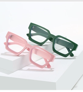 Detail view of pink and dark green thick plastic frames on minimalist geometric blocks