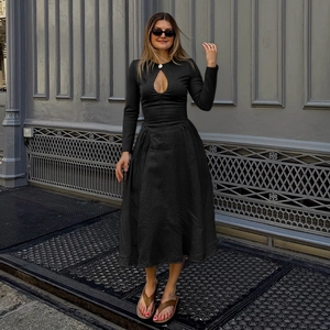 Detail view of stylish long sleeve black dress with elegant hollow neckline and flared hem
