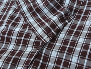 Close-up of brown and blue plaid shirt collar with button detail and fabric texture
