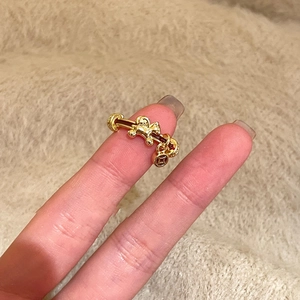 Detail of adjustable gold ring featuring hollow horse design and coin pendants