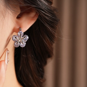 Gros plan d'une boucle d'oreille fleur en argent avec cristaux de zircon portés par un modèle