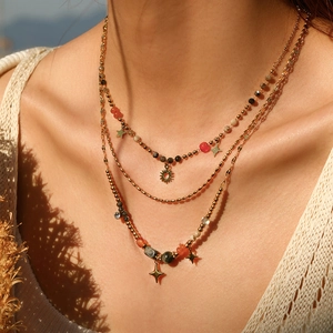 Detail of layered gold stainless steel necklace featuring colorful beads and star pendants