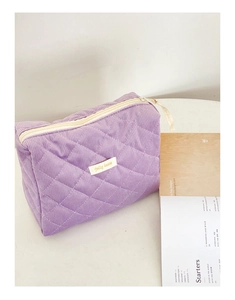 Détail d'une trousse à maquillage en velours côtelé violet avec motif matelassé