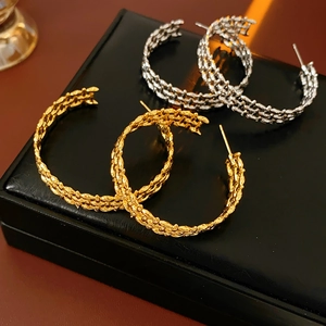 Close-up of gold and silver chunky hollow C-shaped earrings with braided texture detail