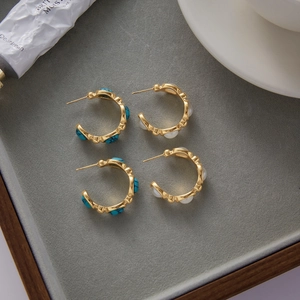 Detail of gold titanium steel hoop earrings with turquoise and white pearls