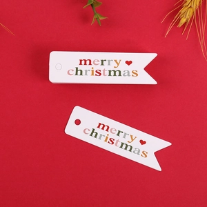 Dettaglio di etichette regalo Merry Christmas bianche con scritte rosse su fondo rosso