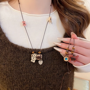Close-up of handmade wooden bear and fox pendants on vintage style cotton cord necklaces