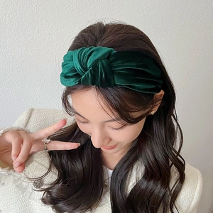 Close-up of a model wearing a deep green velvet knotted wide headband for women