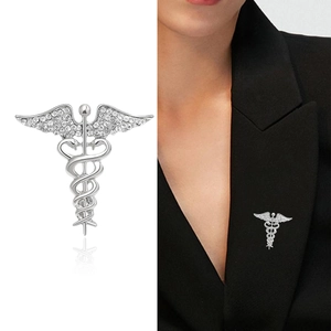 Silver winged caduceus brooch with rhinestones shown on white background and black suit
