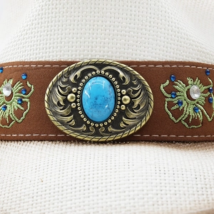 Détail d'un chapeau de cowboy en paille avec bande en daim, turquoise et broderie florale