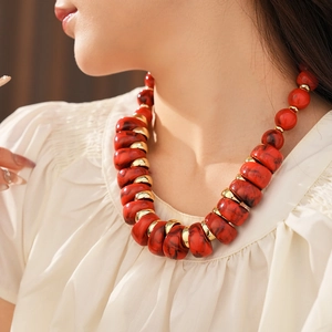 Détail du collier vintage en perles marbrées rouges noires et anneaux dorés sur modèle