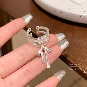 Detail of a matte silver multi-layer ring with an elegant bow pendant on a wooden background