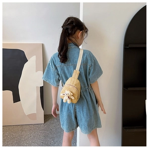 Rear view of a child wearing a cute straw crossbody bag with a plush bear charm