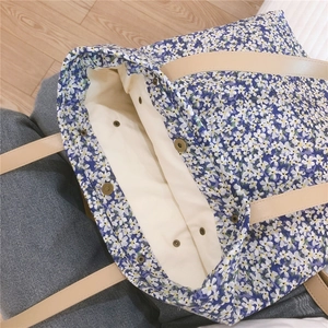 Detail of blue floral tote bag showing metal snap buttons and large interior space