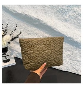 Detail of olive green puffy quilted handbag with floral texture held by a person