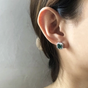 Macro shot of S925 silver stud earring featuring emerald-cut green gemstone on ear