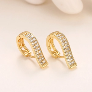 Macro detail of gold-plated J-hoop earrings with pave-set white zircons and hollow patterns