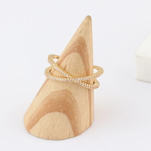 Detail of cross-layered golden ring with pink stones on a wooden jewelry display stand
