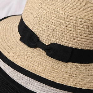 Close-up of woven straw hats featuring a black ribbon bow and fine braided texture