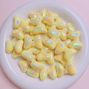 Close-up of yellow butterfly beads with iridescent finish in a white ceramic bowl