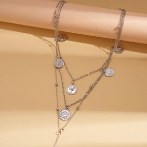 Close-up of layered silver-toned coin pendants with detailed zodiac engravings and portraits