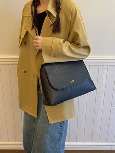 Minimalist black leather shoulder bag with gold logo shown on model for daily commute