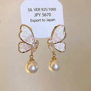 Detail of 925 silver butterfly earrings with sparkling stones and a round pearl charm