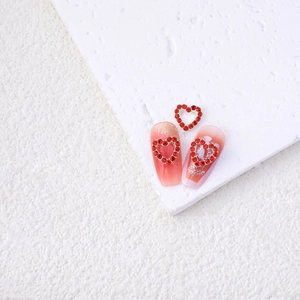 Detailed view of red alloy heart rhinestones on pink gradient nails for Valentines
