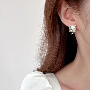 Élégantes boucles d'oreilles carrées en perles baroques et monture dorée sur un mannequin