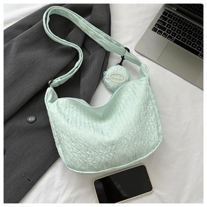 Flat lay of a light green bubble textured crossbody bag with a fashion coin purse on a white sheet