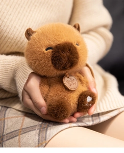 Detailed view of plush capybara toy with Love embroidery on paw and a wooden pendant