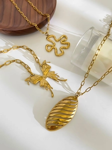 Macro detail of gold butterfly and flower pendants on flat link chains with satin finish