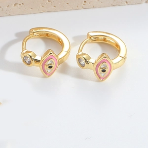 Detailed view of gold hoop earrings featuring pink and black eye motifs and clear stones