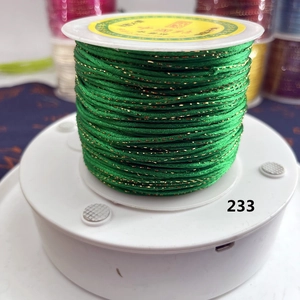 Detail of green and gold braided cord No. 233 on a spool for DIY jewelry making