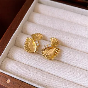 Golden twisted fan-shaped earrings with zircon accents in a luxury jewelry box